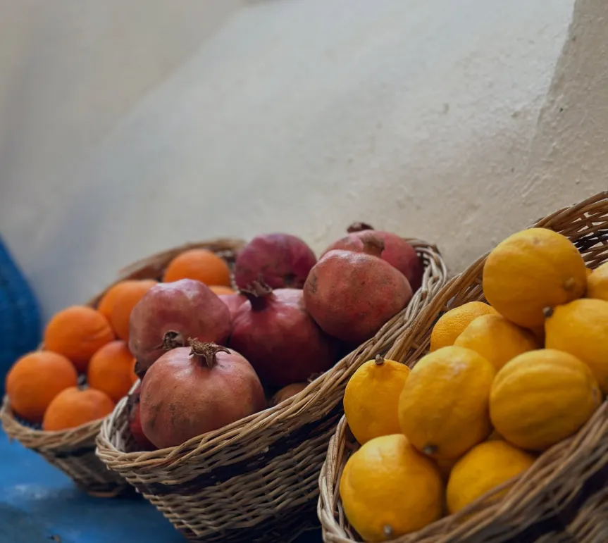 Mavi raf üzerinde portakal, nar ve limon sepetleri